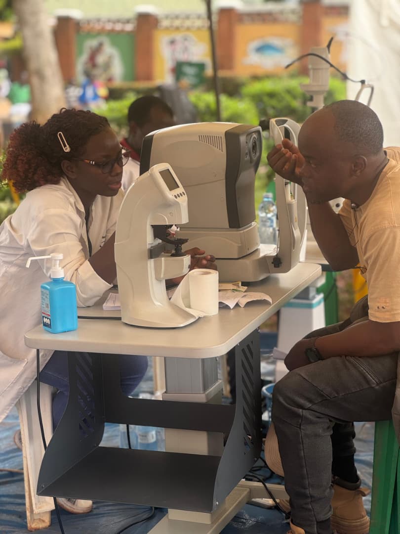 A man has his vision measured with an auto-refractor at a screening station